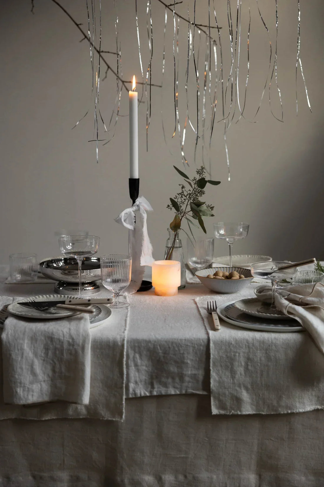 Elegant table setting with TAMEKO natural linen tablecloth, candle, and glassware.