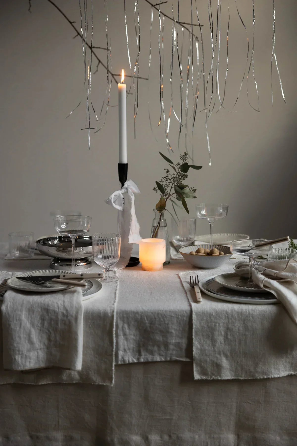 Elegant table setting with TAMEKO natural linen tablecloth, candle, and glassware.