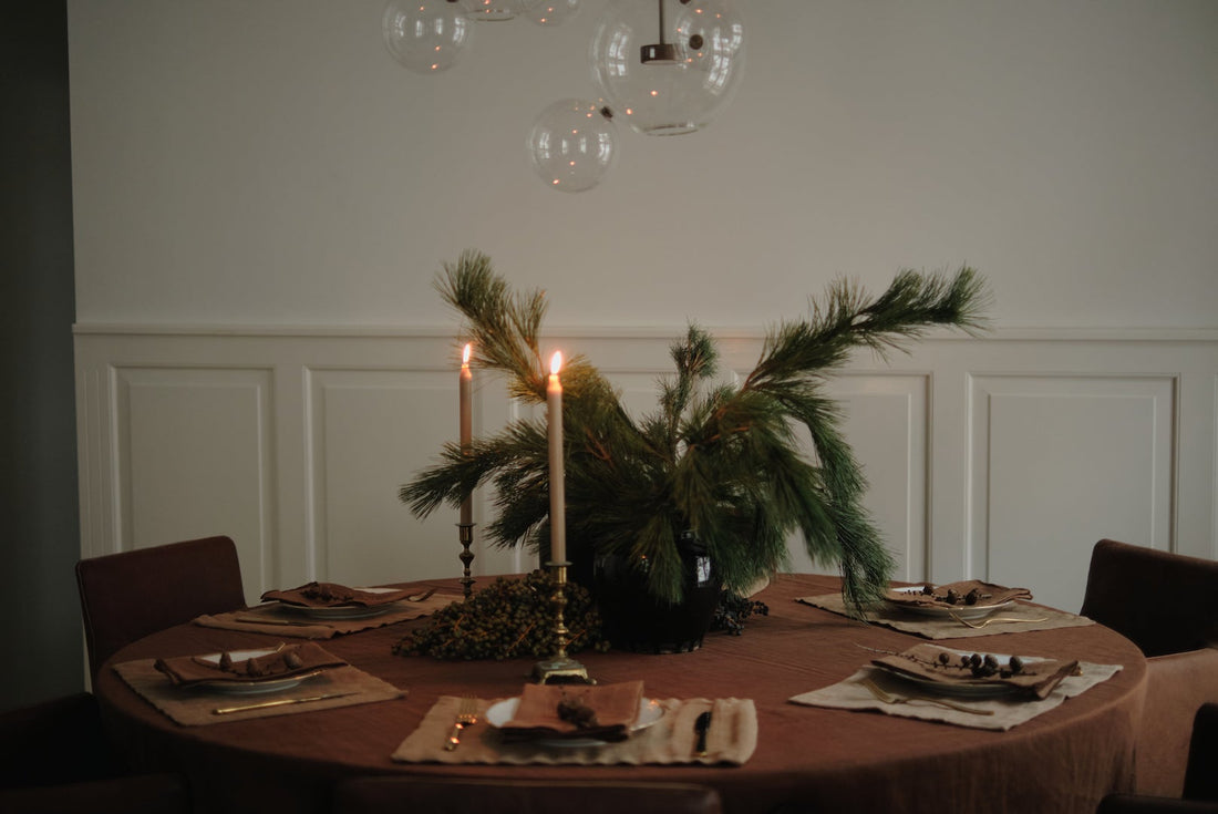 Elegant table setting with rust TAMEKO tablecloth, ochre placemats, brown napkins, greenery and candles