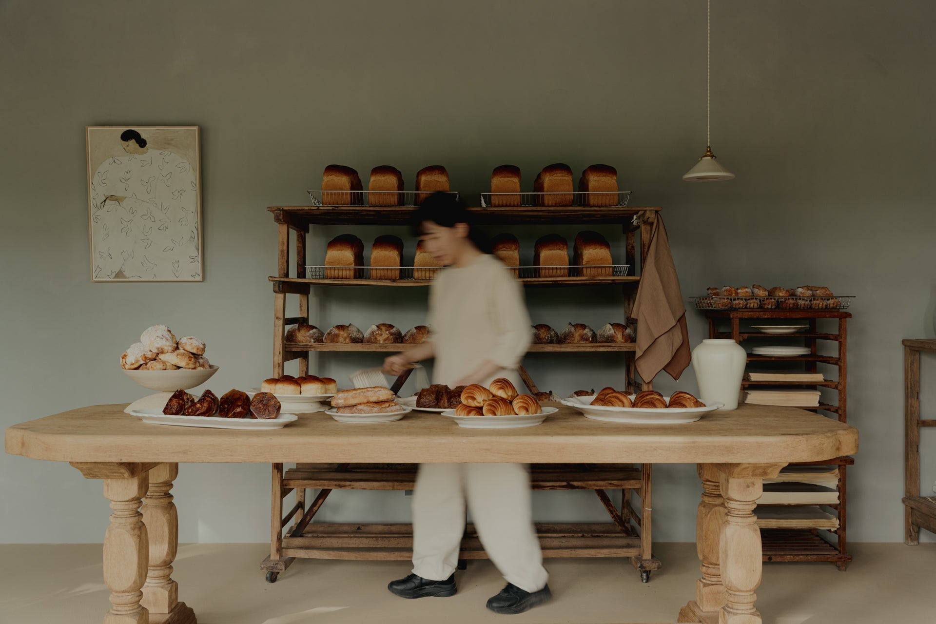 Artisan bakery breads and pastries on wooden table, cozy rustic interior, TAMEKO style.