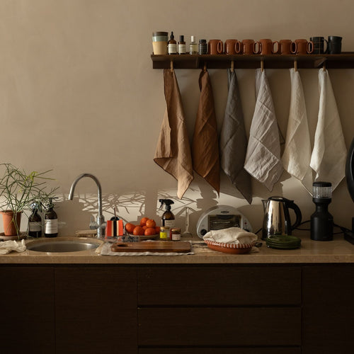 Minimalist natural kitchen with beige and brown towels, mugs, and TAMEKO home fabrics