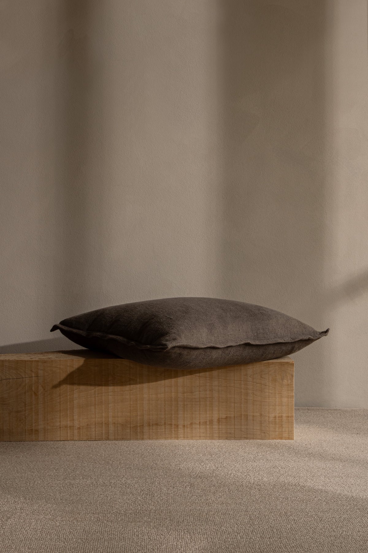 TAMEKO Drift Cushion Dusk by Norm Architects, dark fabric pillow on wooden bench, minimalist home decor