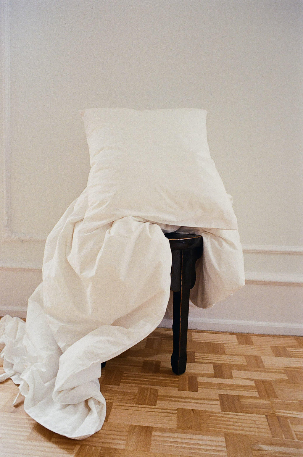 Neutral-toned pillow and duvet on a dark wood bench, TAMEKO home textiles, minimalist style