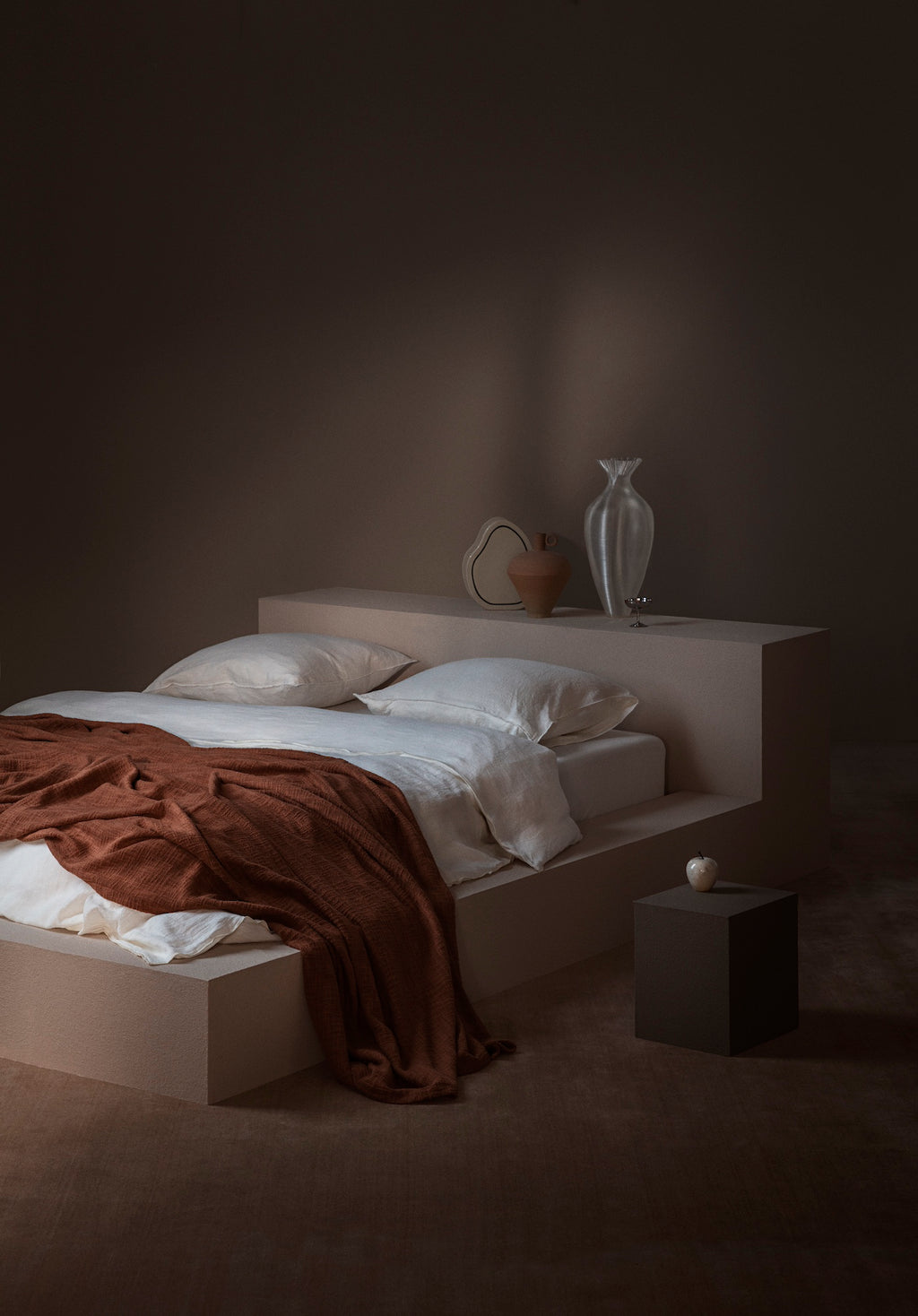 Minimalist bedroom with TAMEKO bed linens, rust throw, neutral pillows, and decorative vases.