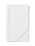 TAMEKO white linen table runner with natural texture and raw edges, folded on a white background