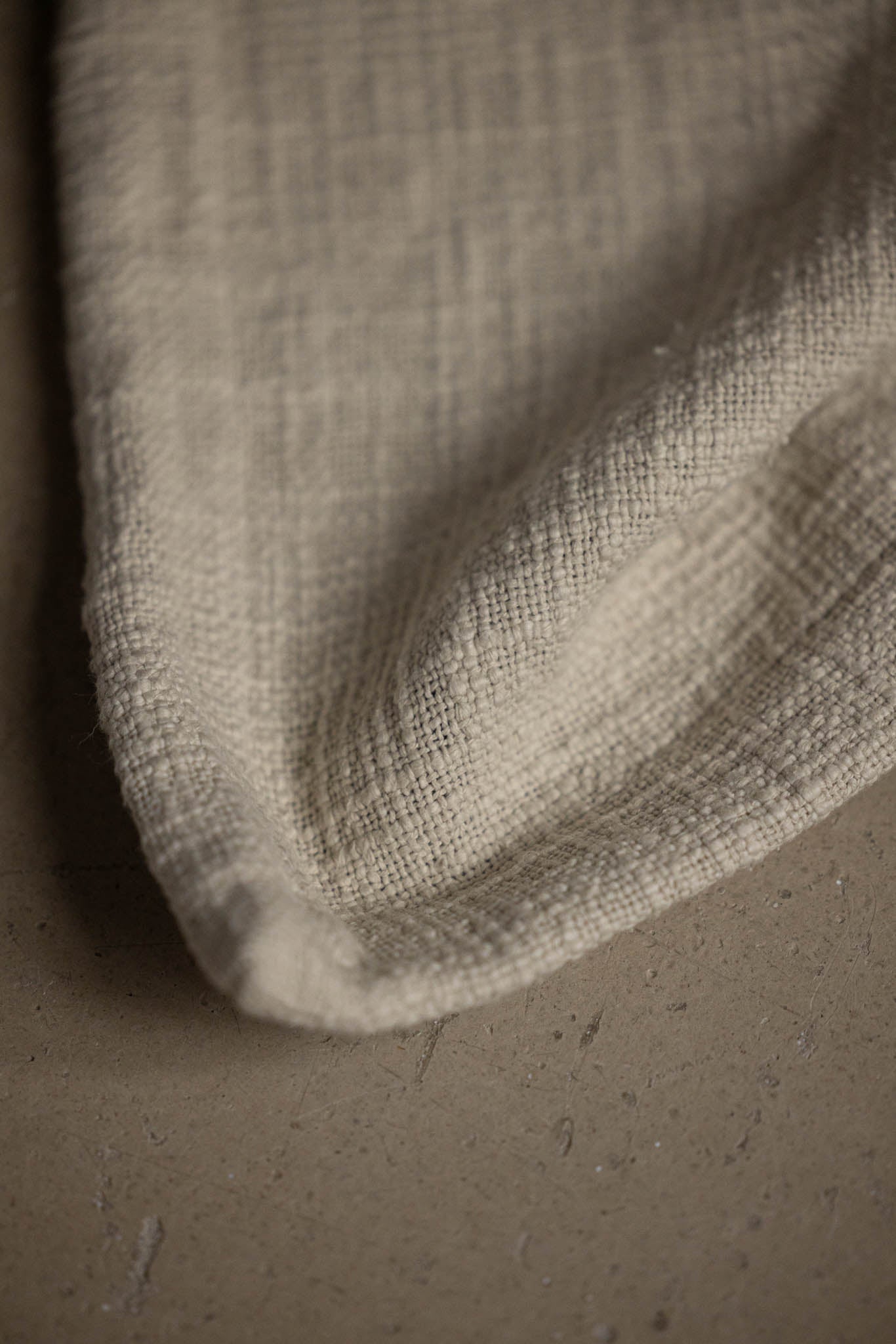 Natural woven fabric close-up on neutral surface, TAMEKO home textile detail