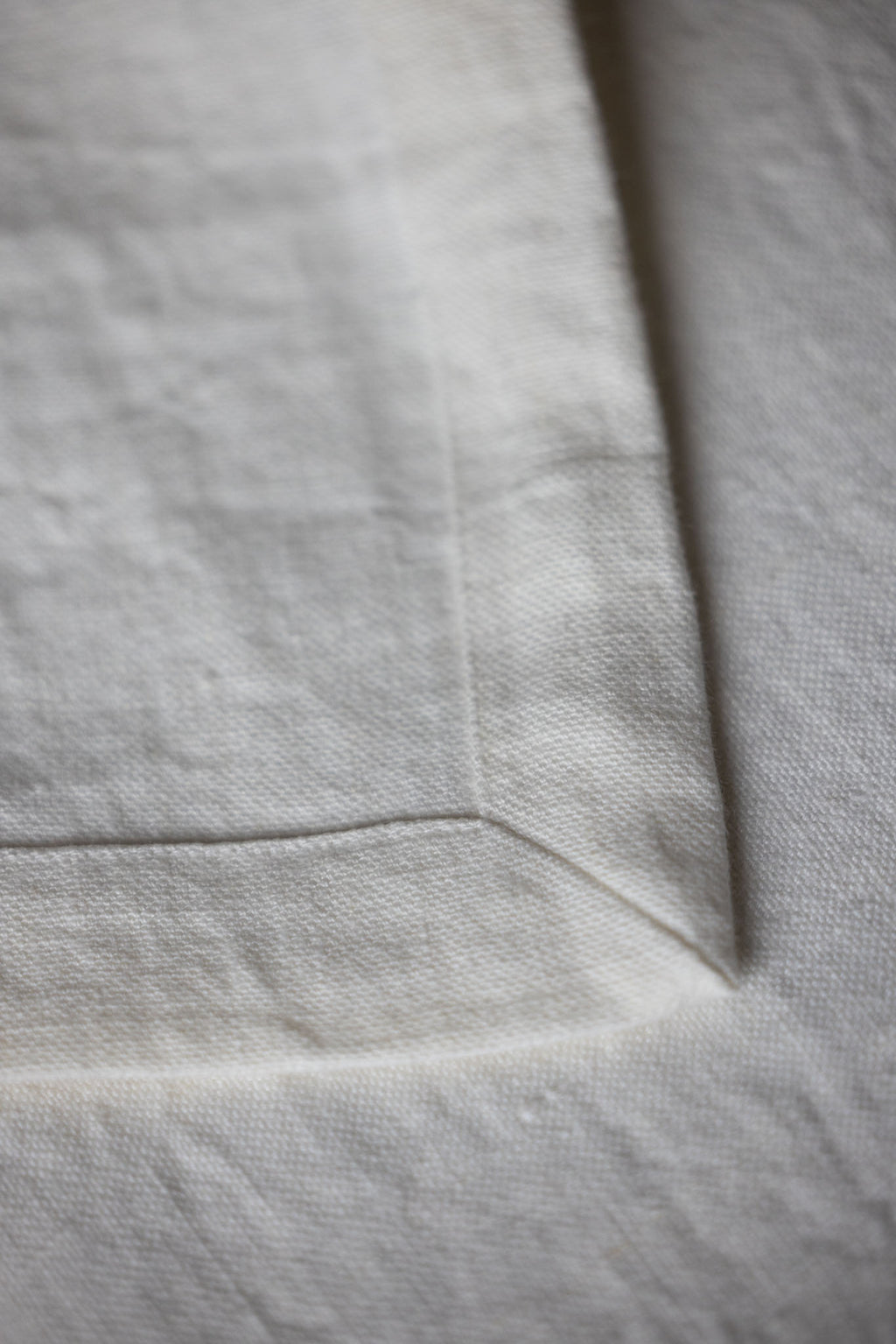 Close-up of natural linen fabric with stitched hem, TAMEKO home textiles detail