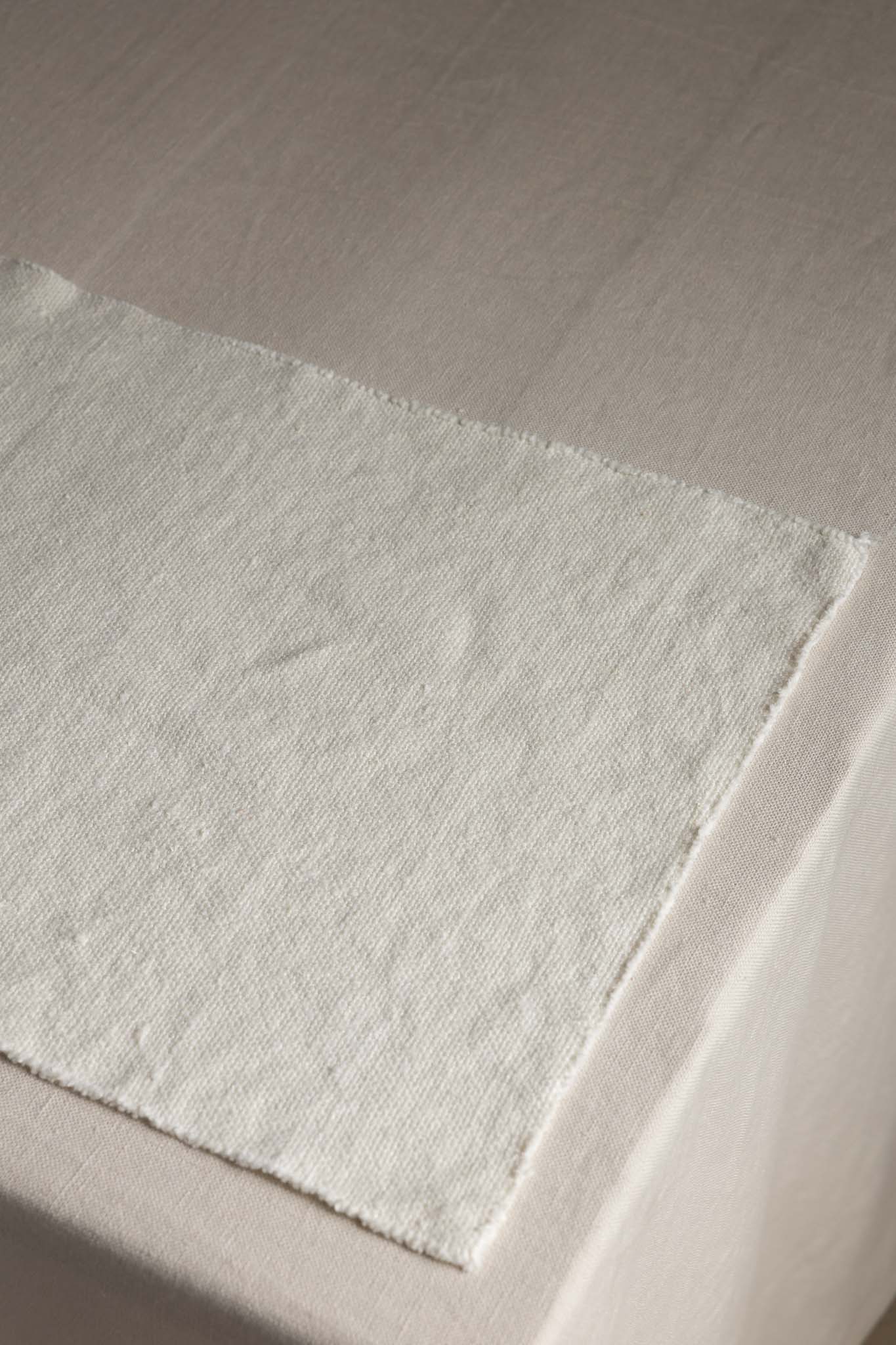 Natural woven linen fabric swatch on beige tablecloth, TAMEKO home textiles