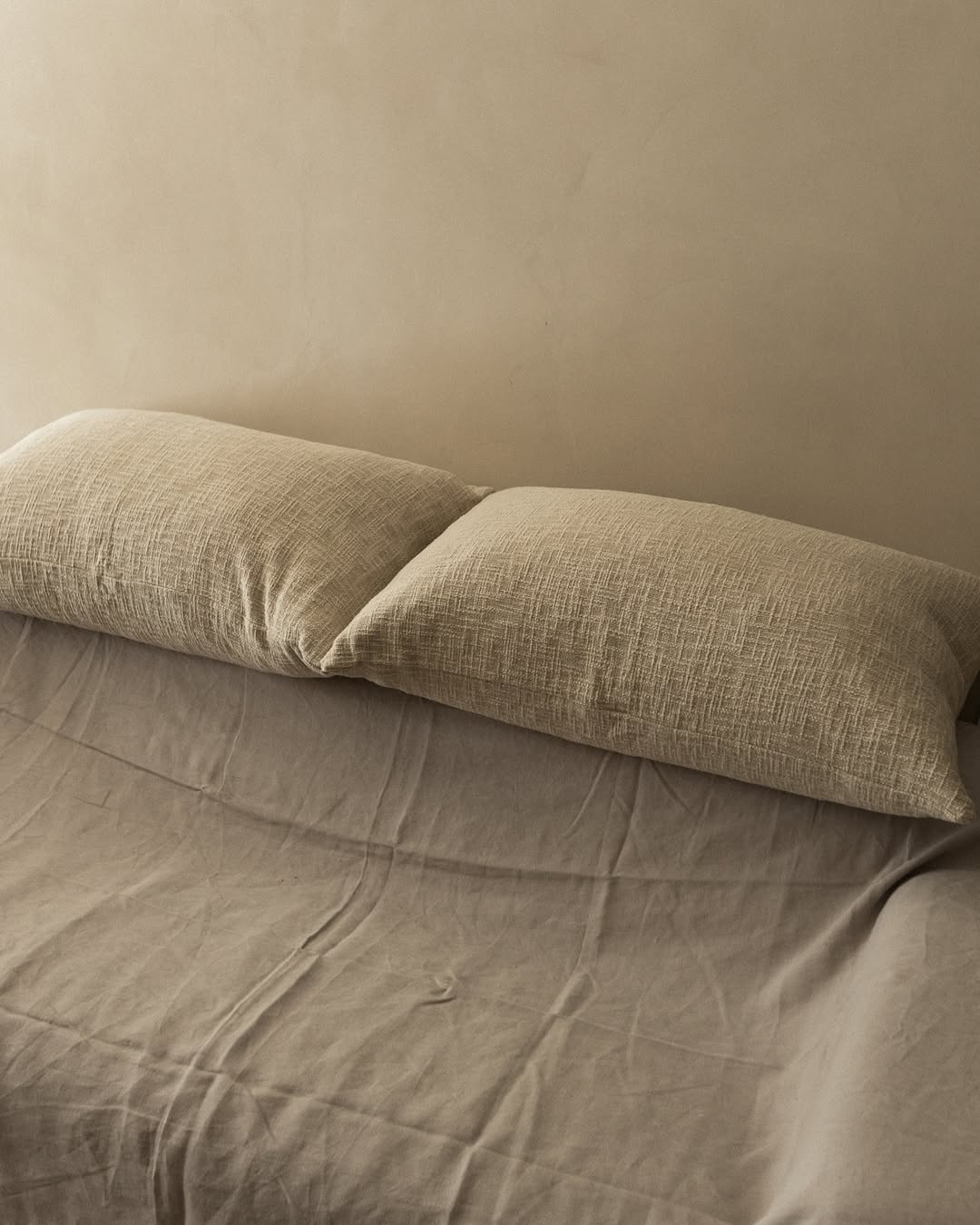 Neutral linen bed with two textured beige pillows, minimalist TAMEKO home textiles